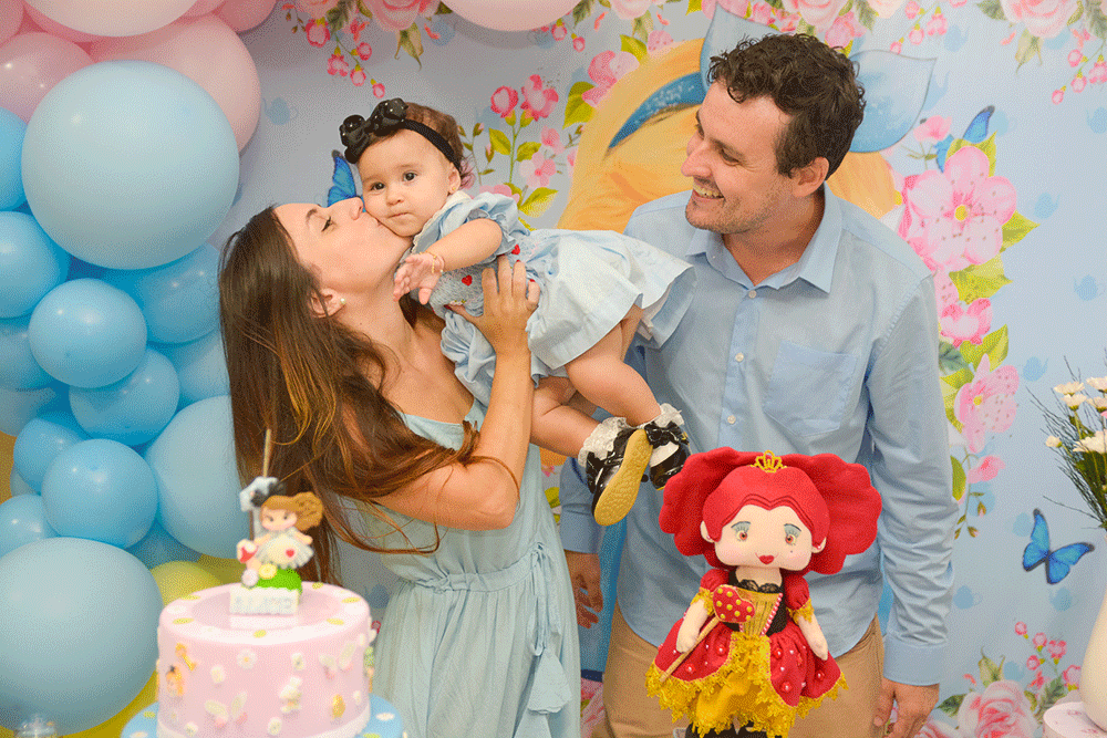Foto Festa Infantil de Pai com a Mae beijando a filha na frente da mesa do bolo.